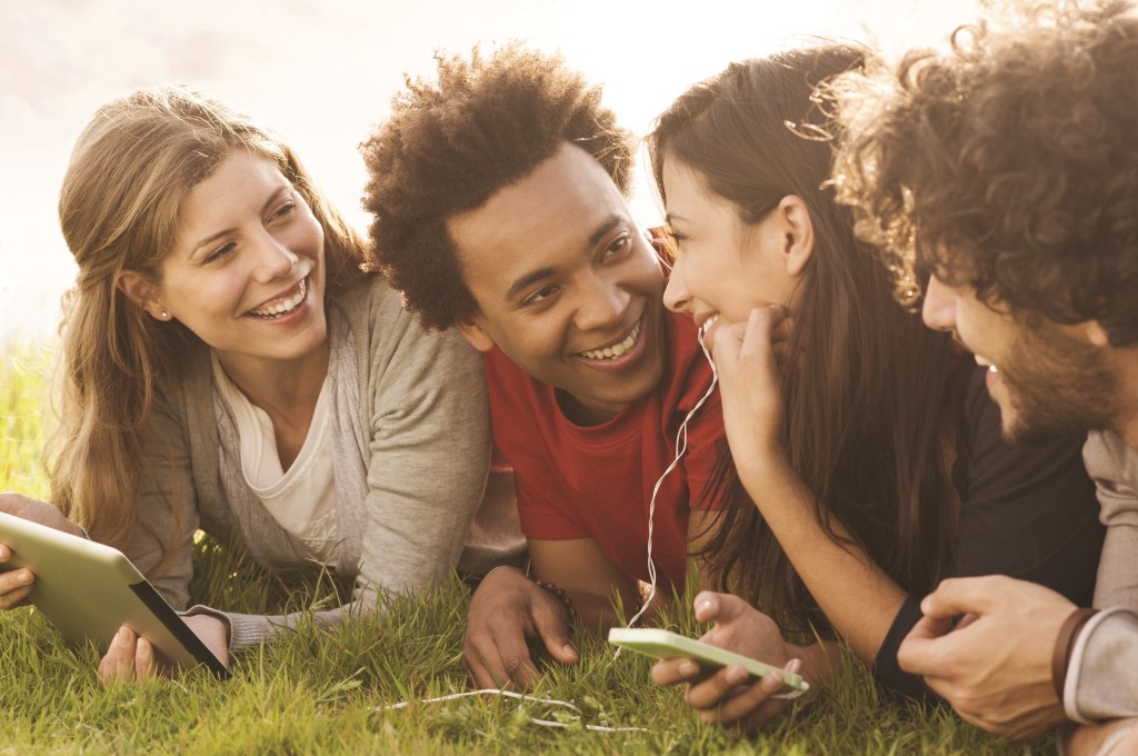 Lying in a field with a phone and a tablet, laughing