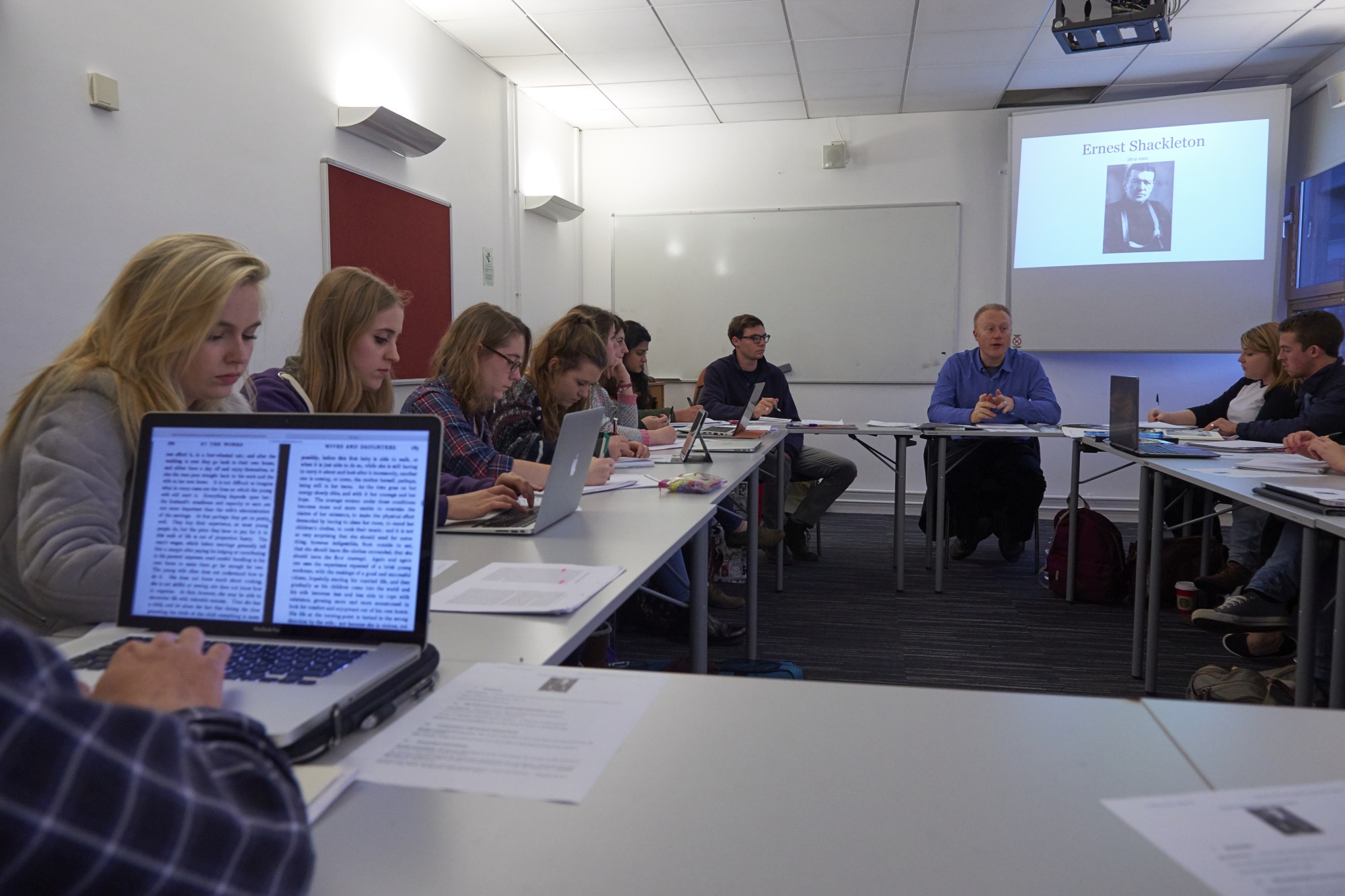 Lecture with students sitting at tables in a small room